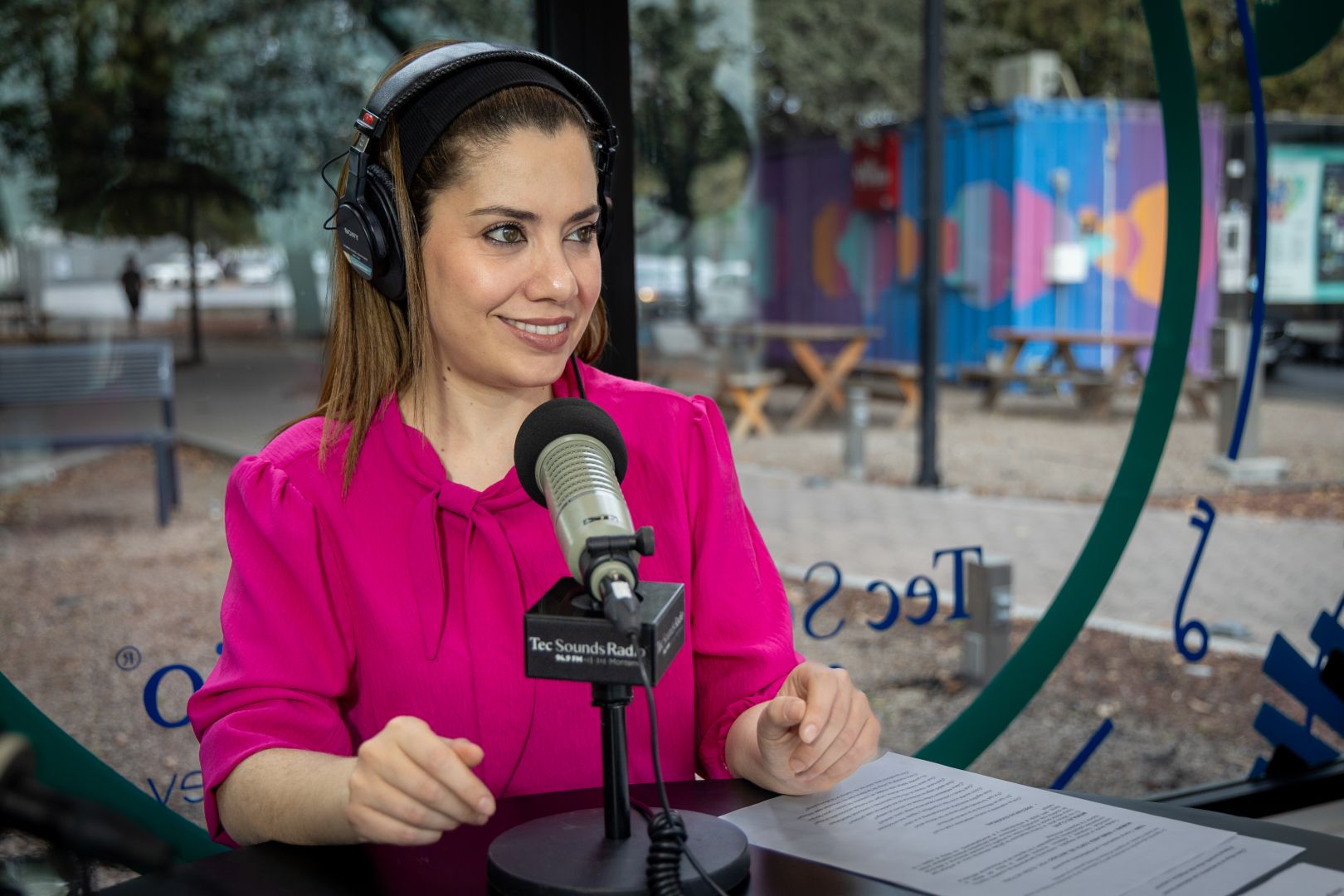 Conductora de radio con aud&iacute;fonos habla frente a un micr&oacute;fono de Tec Sounds Radio durante la grabaci&oacute;n del programa.