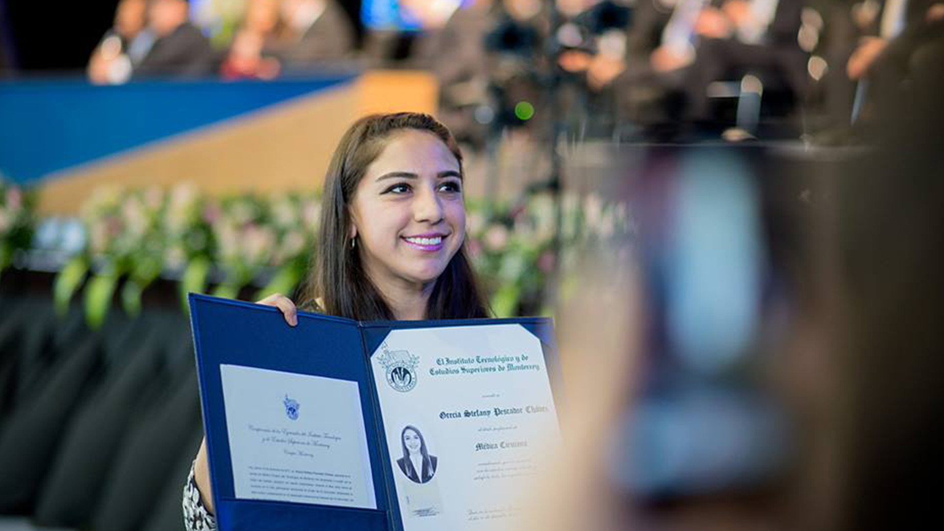 Mujer sosteniendo título  profesional mientras es fotografiada