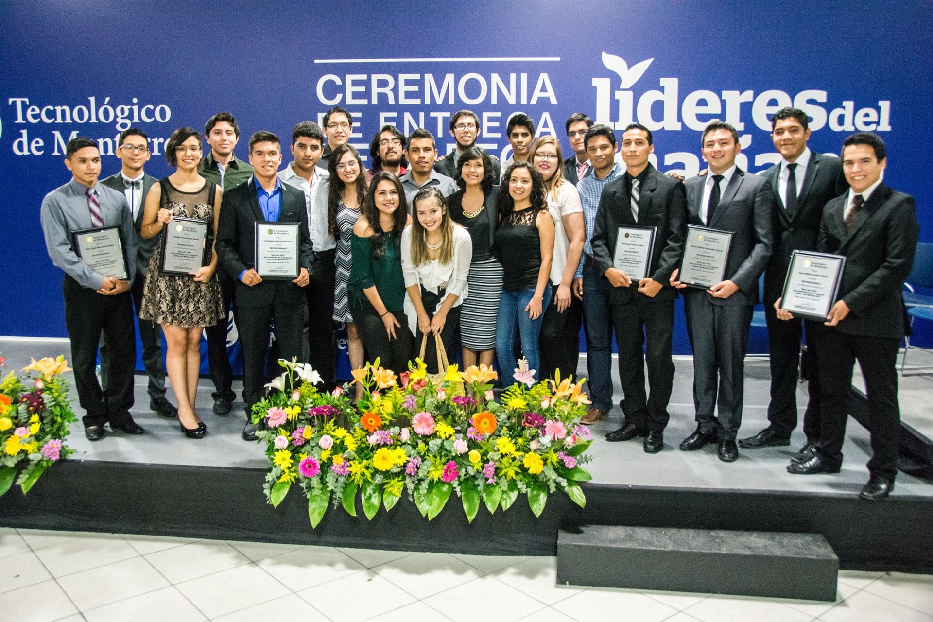 Grupo de jóvenes abrazados con diplomas