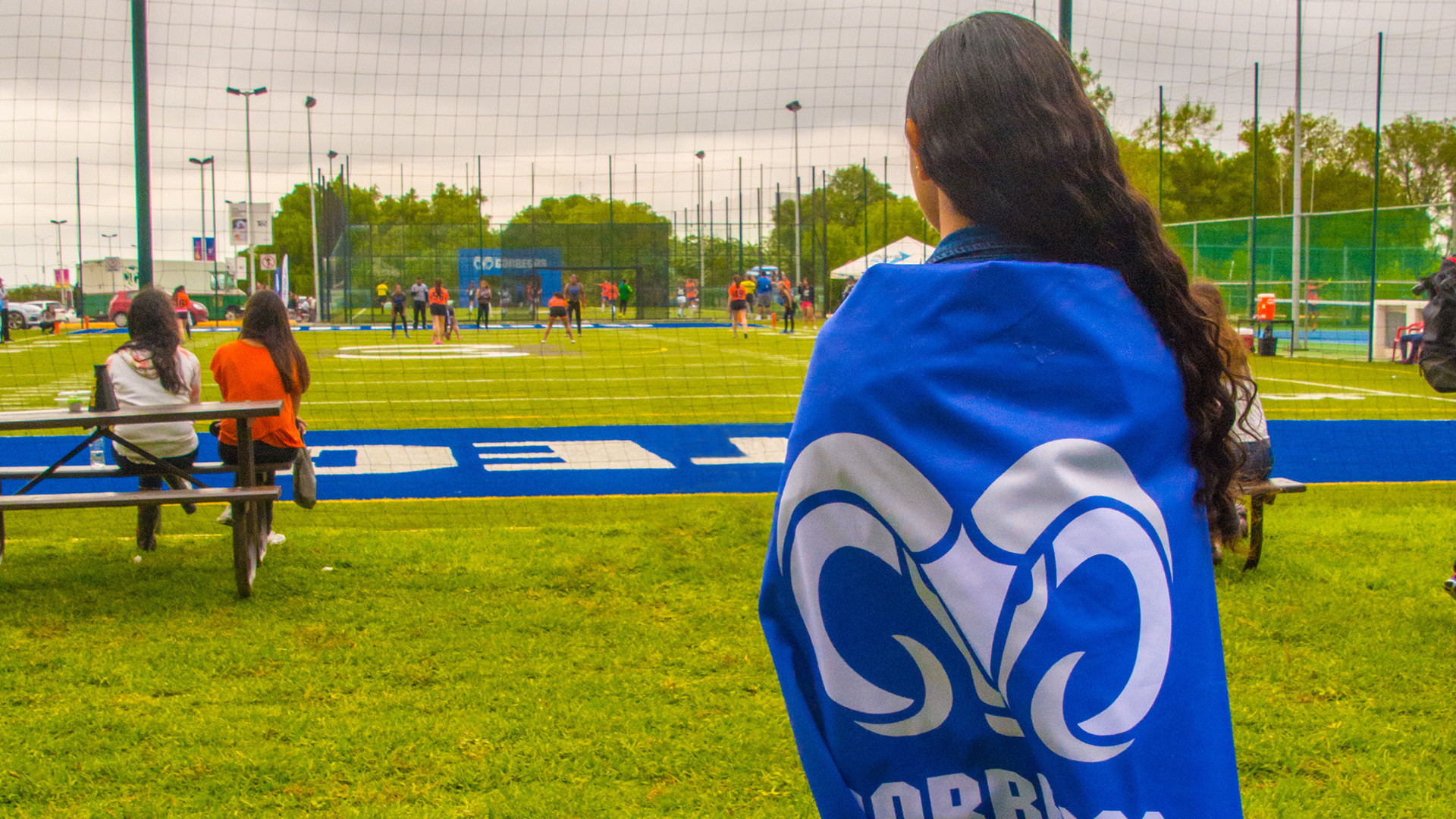 Mujer parada cubriéndose del frío con una bandera de Borregos Tec