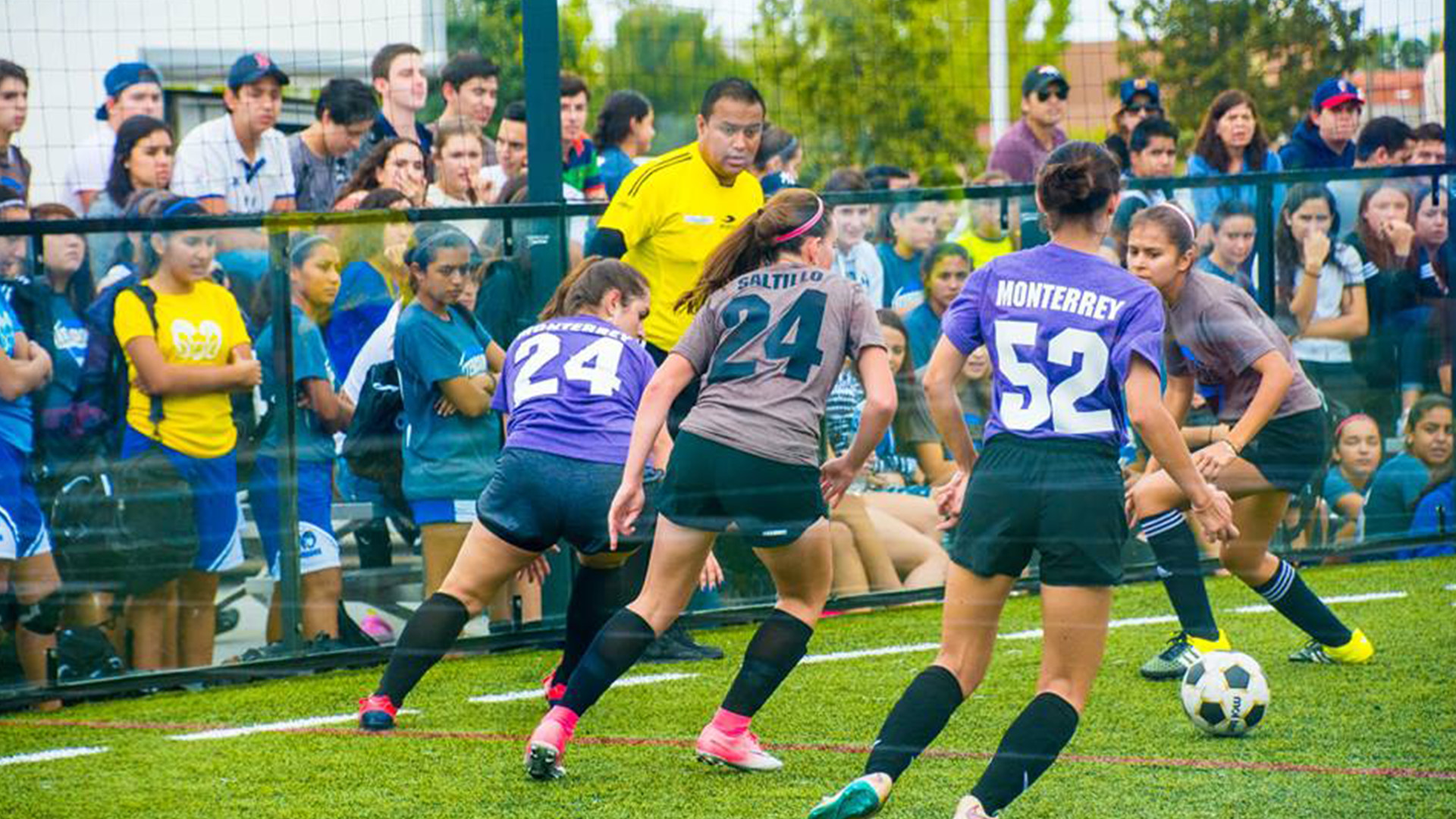 Jóvenes jugando fútbol en una cancha de pasto sintético