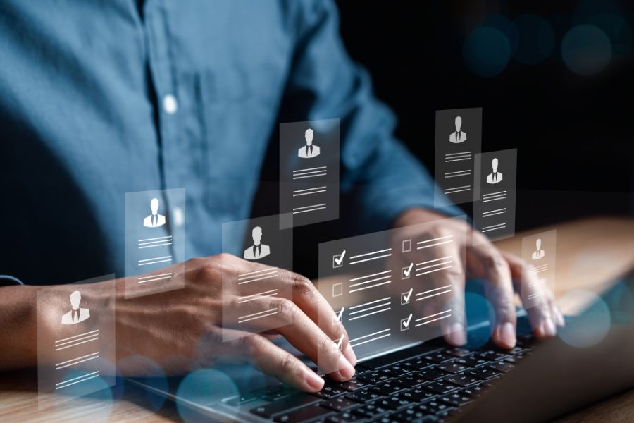 Persona utilizando una computadora port&aacute;til mientras se visualizan interfaces digitales con perfiles de usuario, listas de verificaci&oacute;n y datos protegidos, que representan el acceso controlado a informaci&oacute;n personal en plataformas tecnol&oacute;gicas.