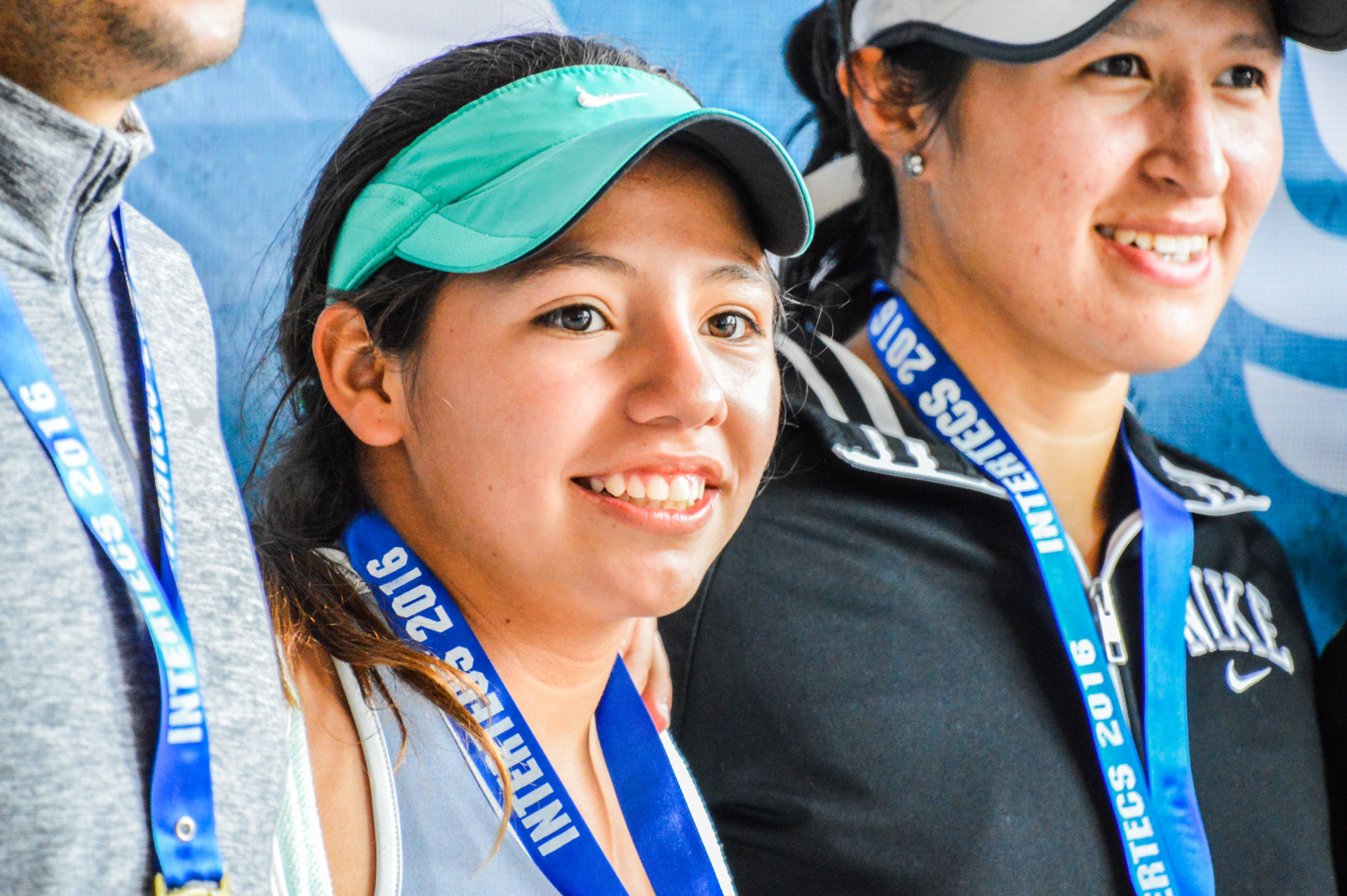 Joven mujer con medalla en el cuello sonriendo hacia la derecha