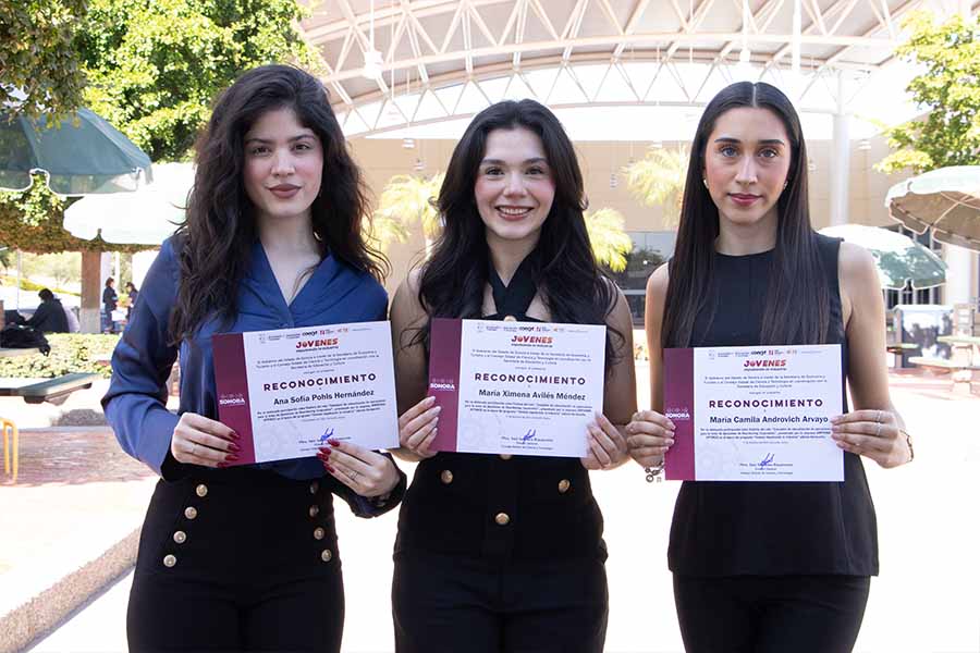 Tres mujeres j&oacute;venes sosteniendo reconocimientos de primer lugar.