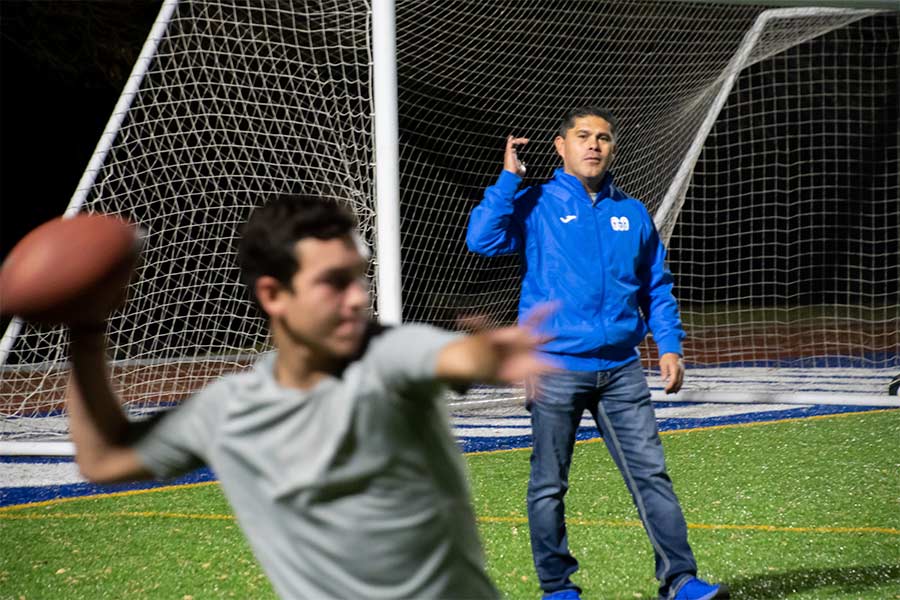 El coach dando indicaciones a un jugador mientras lanza el balon