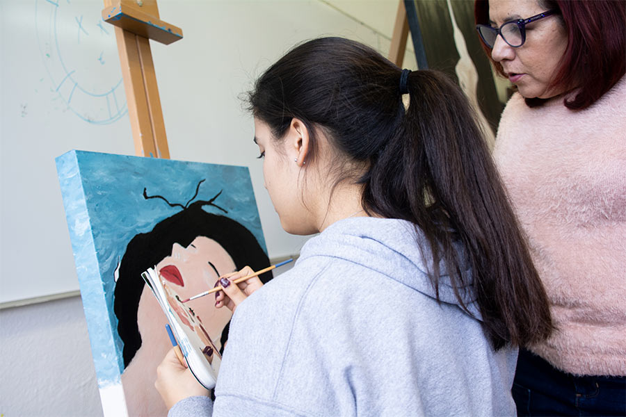 Maestra de pintura con su alumna trabajando en una pintura