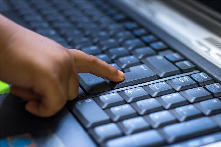 Niño presionando botón de teclado de computadora