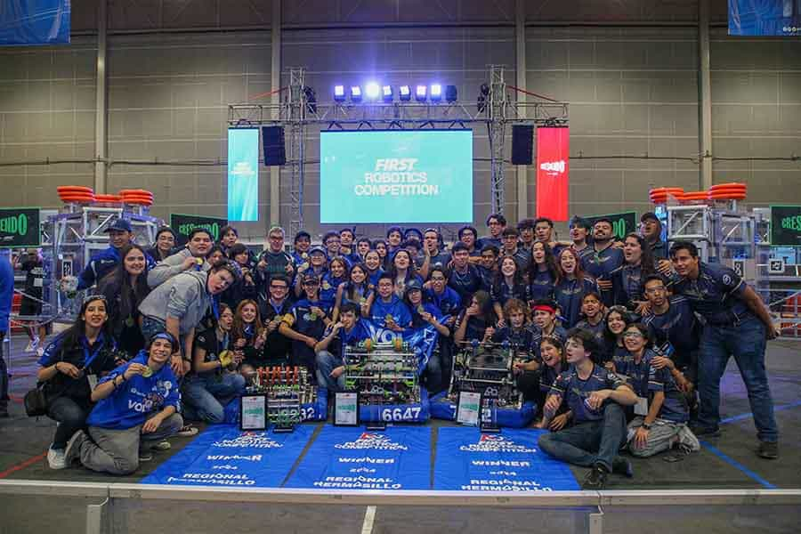 Equipos de la alianza azul posando con sus robots en la cancha de FIRST.