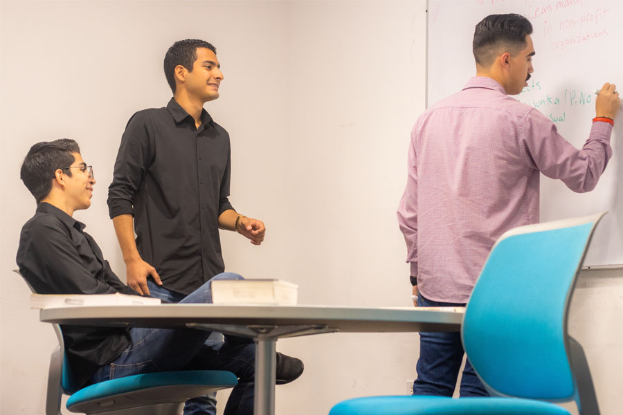 alumnos de ingenieria reunidos hablando de su paper en oficina