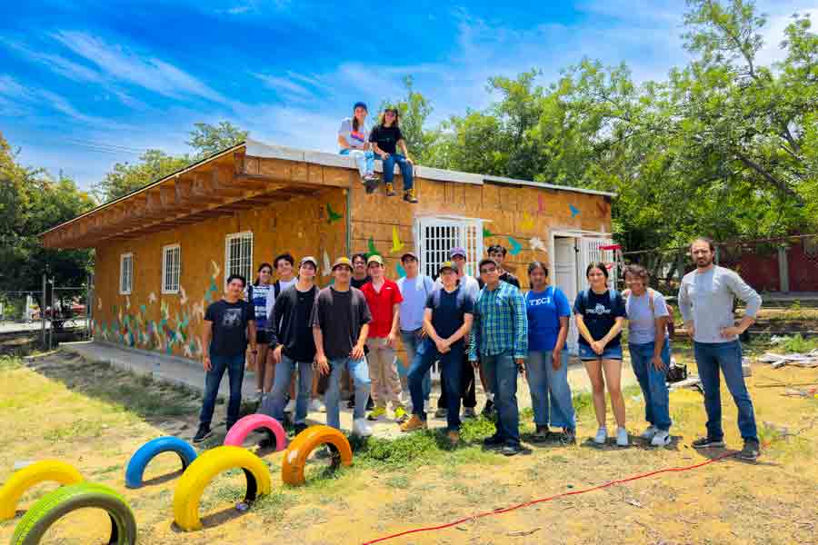 Alumnos participantes en la construcción del aula posan frente al salón.