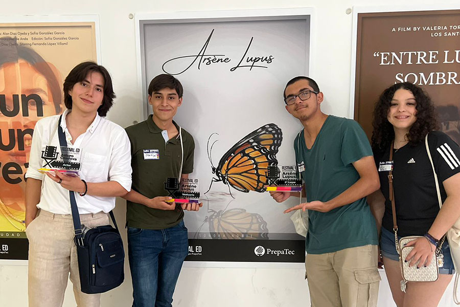 Los estudiantes que produjeron Arsenè Lupus posando frente al póster de su corto con los premios que ganaron.