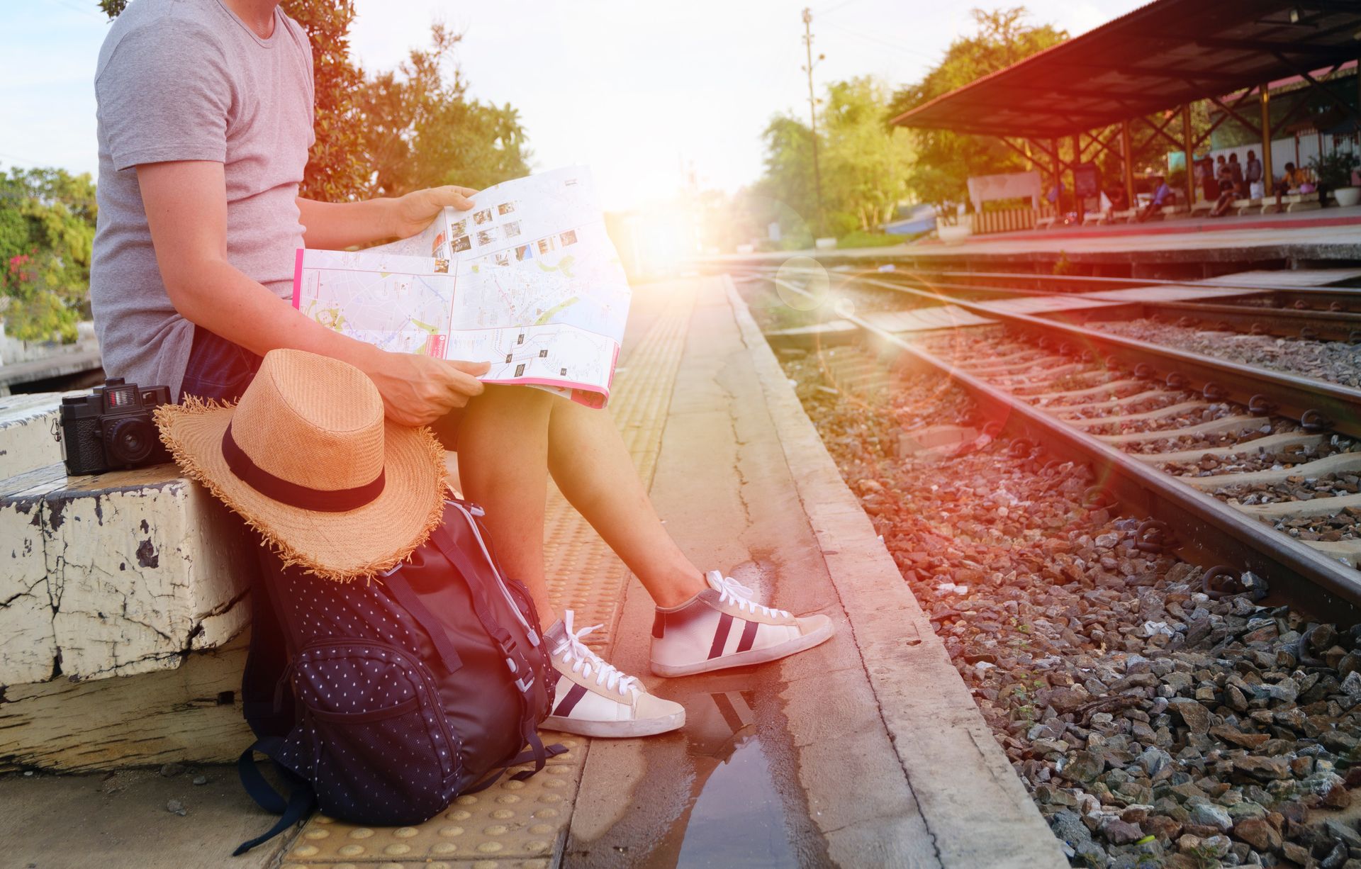 Joven esperando el tren con un mapa en las manos