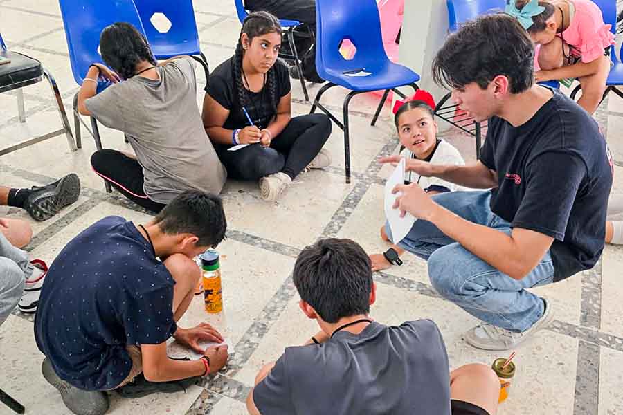 Un joven sentado junto a un grupo de ni&ntilde;os.