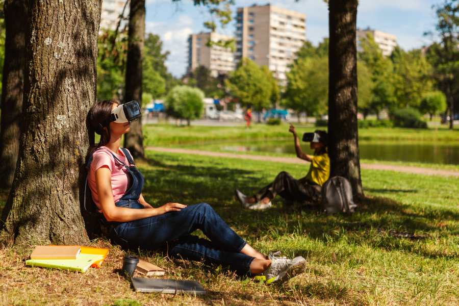 2 chicas jóvenes con visores de realidad virtual y libros alrededor