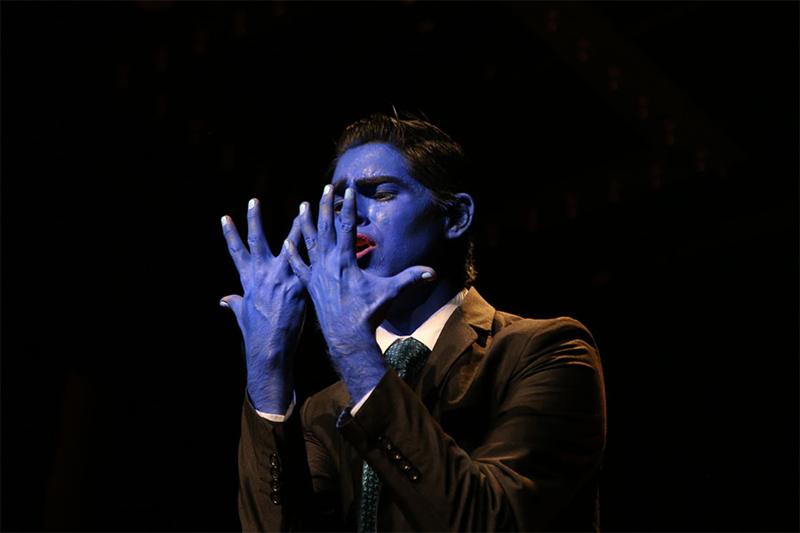 Joven vestido de traje con la cara y las manos pintadas de azul. 