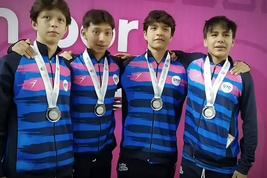 Diego Lizardi, Omar Ruelas, Isaac Vite y Matías Castillo, medallistas de plata en la prueba de relevos 4x100 en el Grand Prix, posan juntos con sus medallas sobre un fondo rosa.