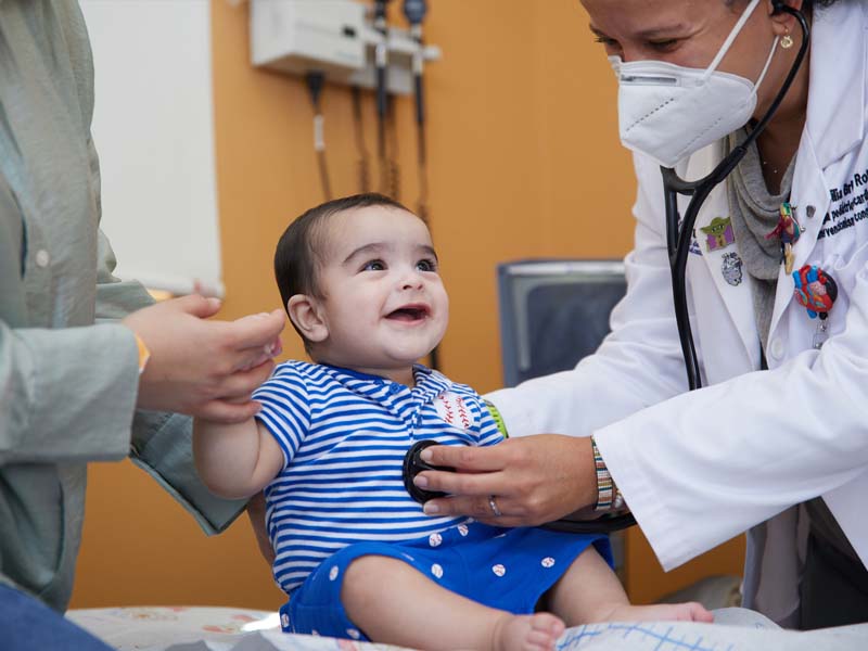 Doctora Cecilia Britton revisando la salud de un paciente pediátrico.