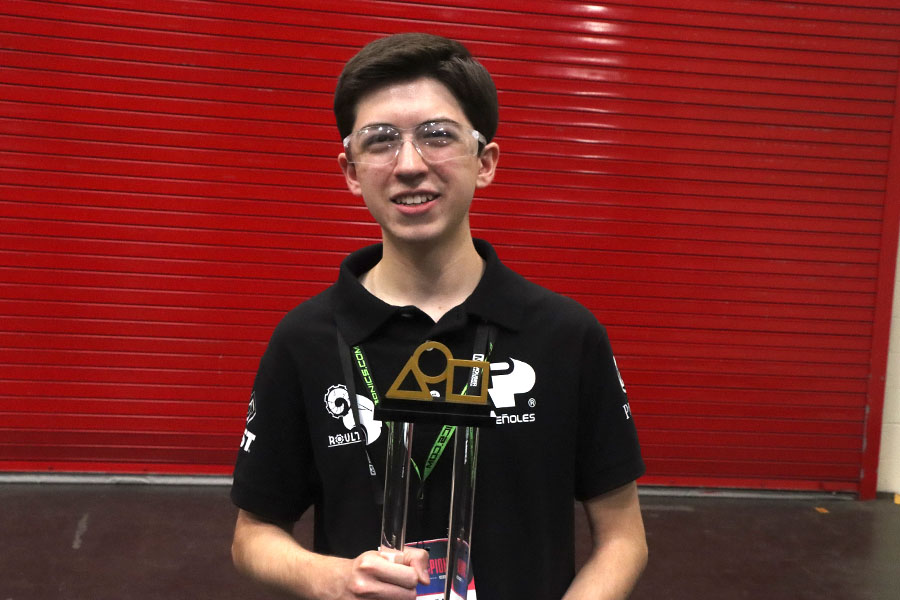 Joven de PrepaTec Laguna posa para fotografía con uno de sus logros internacionales, el trofeo de un mundial de robótica