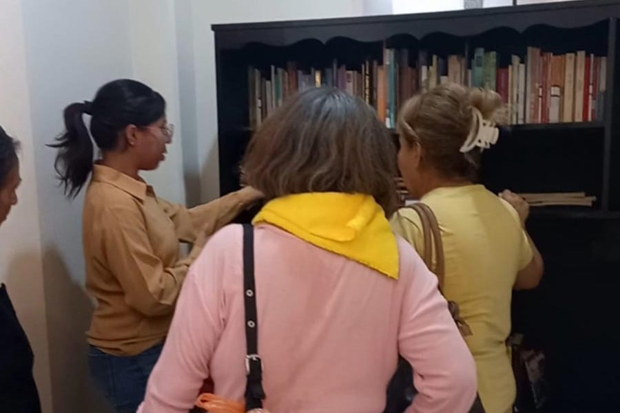 Viridiana explica a 3 adultos mayores sobre la biblioteca, en el centro gerontológico de Guanajuato.