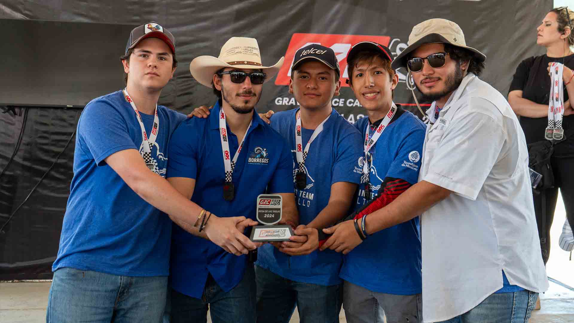 grupo de alumnos en uniforme posan frente a la cámara sosteniendo su premio de desempeño