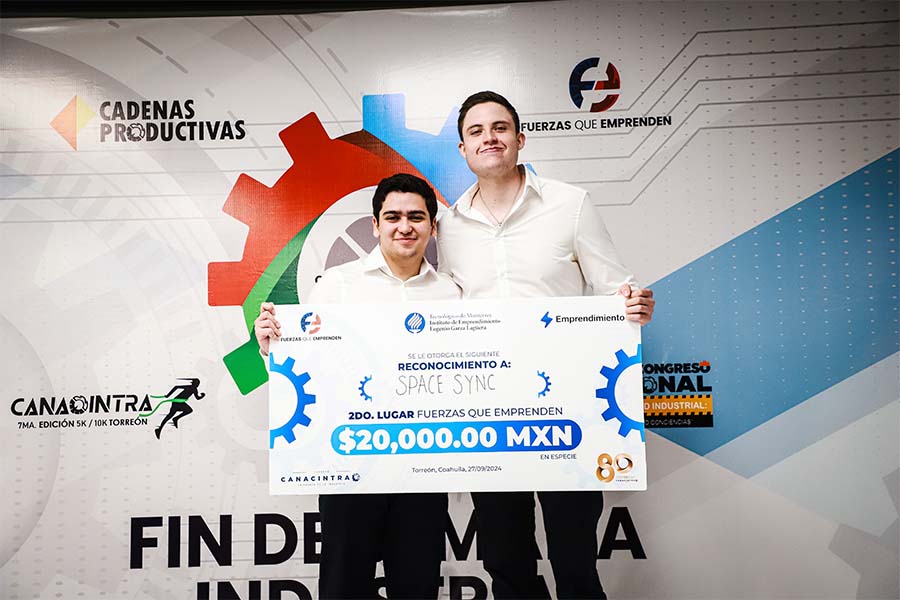 2 estudiantes del Tec de Monterrey posan con un cheque al ser ganadores de un concurso de emprendimientos organizado por CANACINTRA Torreón