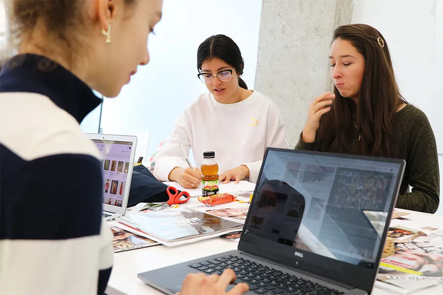 Alumnas de estudios creativos diseñando e investigando en sus computadoras