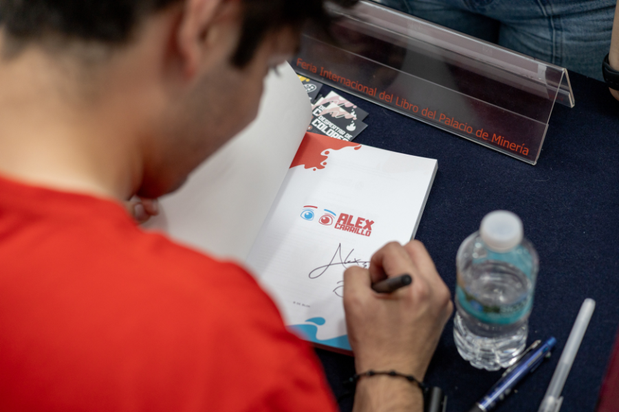 El ilustrador Alex Carrillo firma ejemplares de su primer libro infantil durante la Feria Internacional del Libro.