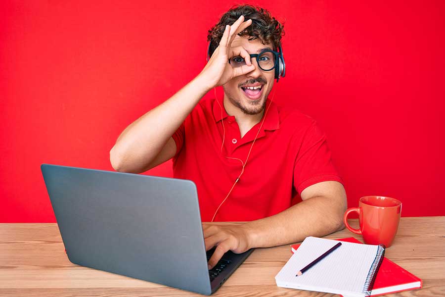 Joven trabajando en computadora, haciendo una señal de aprobación con su mano