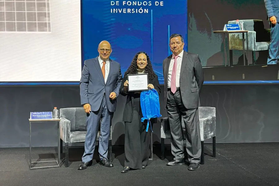 Alumna posando con dos empresarios mientras recibe su dipoloma de segundo lugar del concurso de videos Fondos de Inversión..