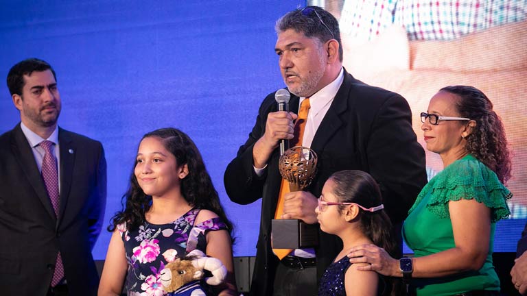 Profesor inspirador dando un discurso al recibir su premio junto a su familia