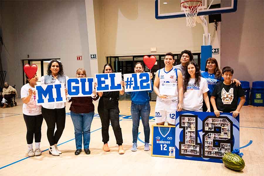 Miguel, egresado del Tec de Monterrey campus Laguna, posa con su familia para una fotografía en la duela de la arena de básquetbol de Borregos Laguna