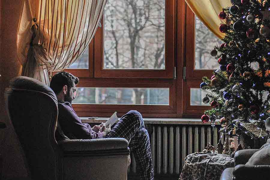 Joven adulto leyendo, se aprecia un árbol de navidad en la habitación