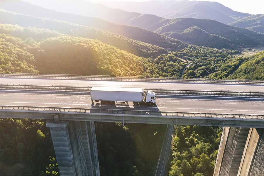 Trailer manejando sobre puente rodeado de árboles