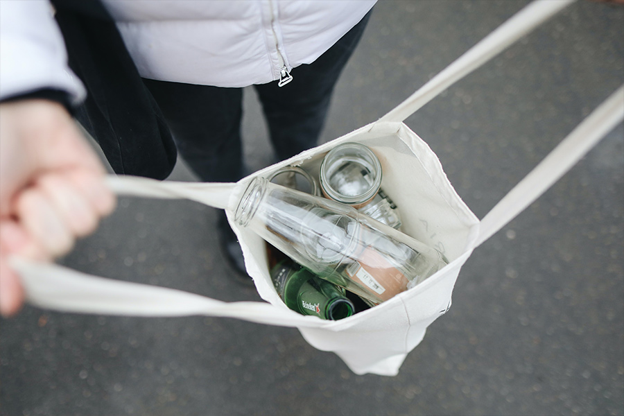 Mujer cargando bolsa con botellas de vidrio