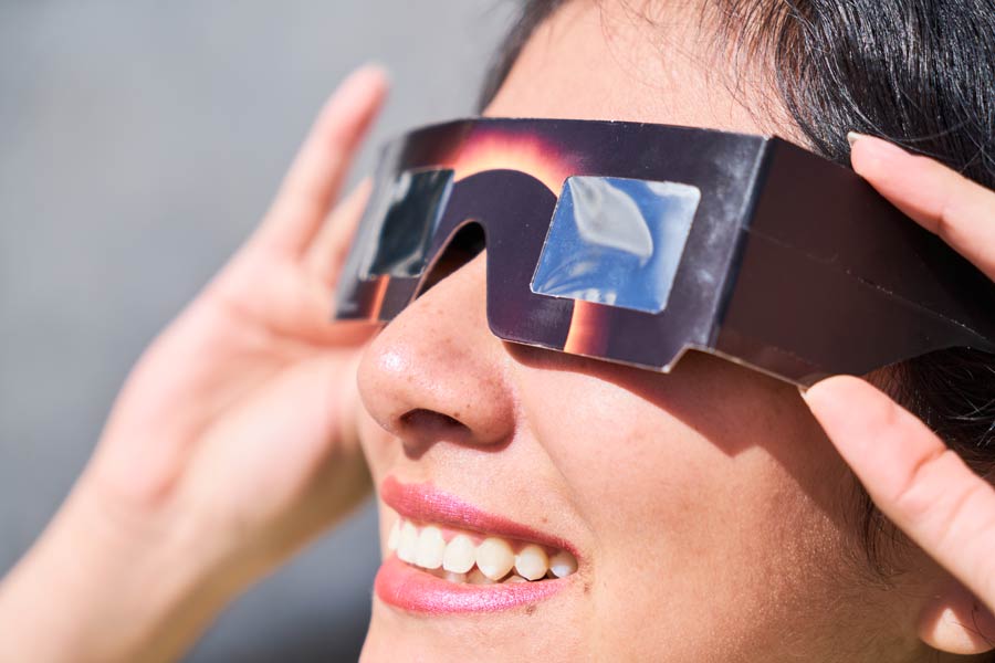 Mujer sonríe viendo el eclipse solar.