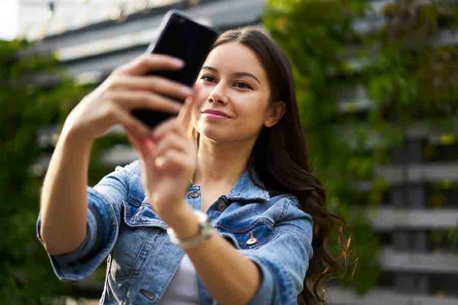 Mujer tomándose una selfie con su celular en un espacio abierto.