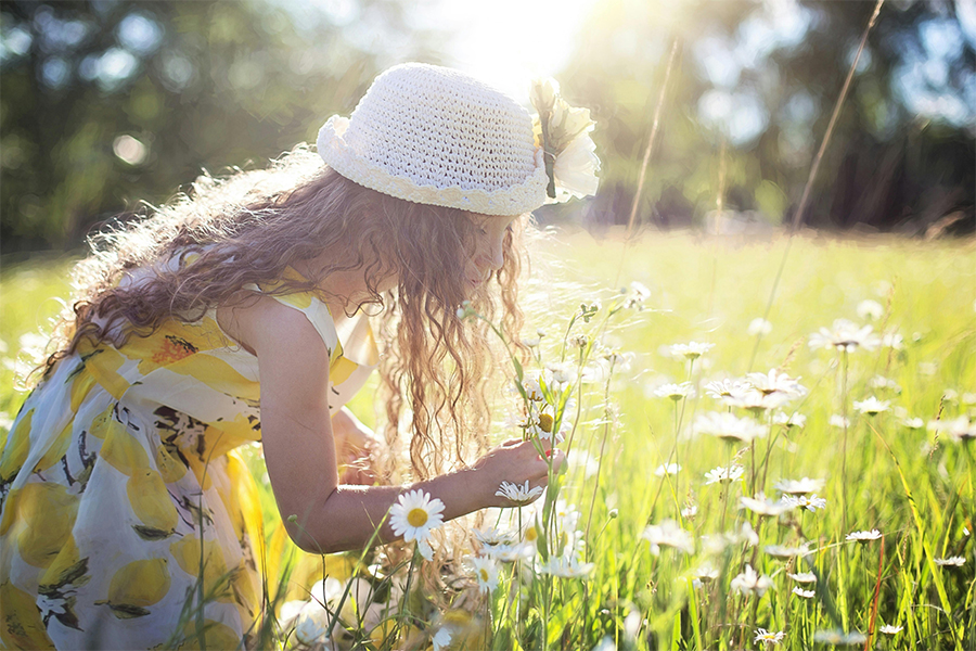 Niña oliendo flores