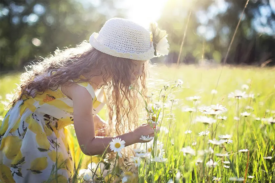 Niña oliendo flores