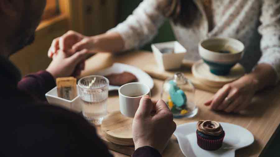 Pareja sosteniendo sus manos en una mesa con postres