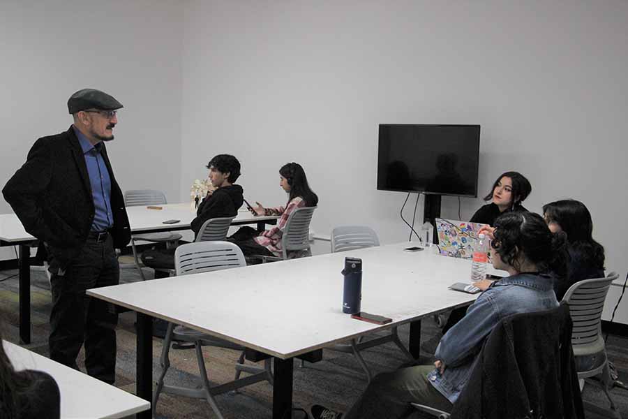 El profesor imparte clases a alumnos y alumnas de estudios creativos. 