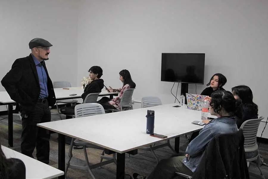 El profesor imparte clases a alumnos y alumnas de estudios creativos.