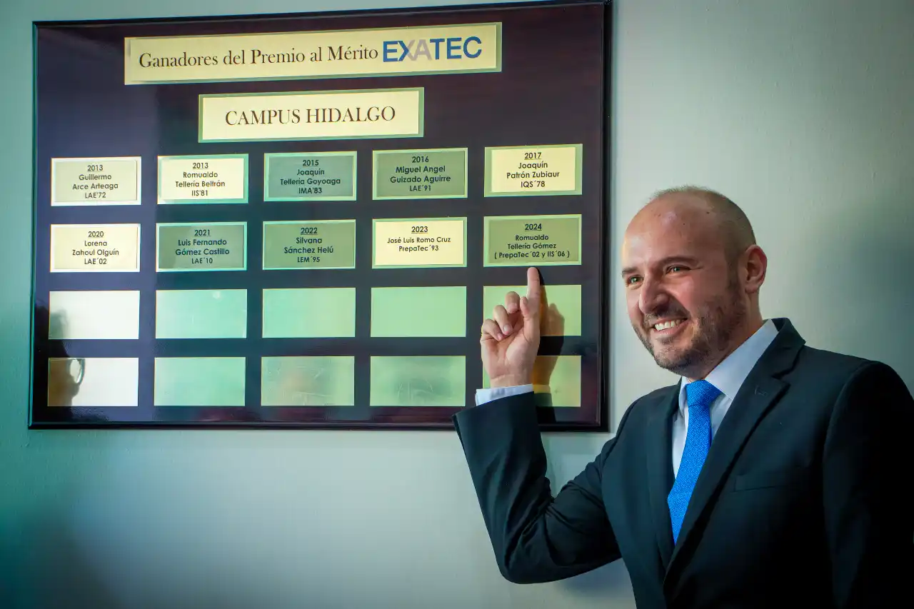 Ingeniero Romualdo Tellería posando frente a placa de Mérito EXATEC