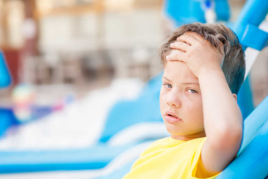 Niño al aire libre, con gesto que puede indicar que presenta un golpe de calor