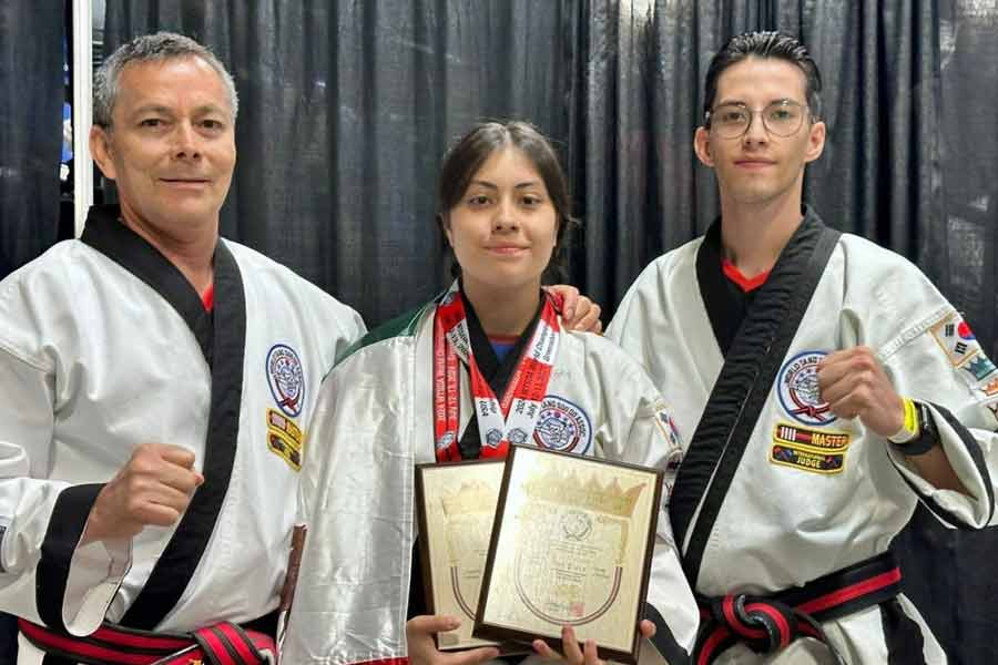 Sara Ramírez, campeona de Tang Soo Do, posa con sus maestros mientras sostiene sus premios y medallas.