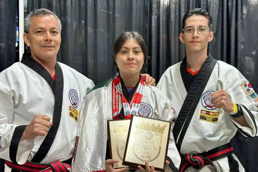 Sara Ramírez, campeona de Tang Soo Do, posa con sus maestros mientras sostiene sus premios y medallas.