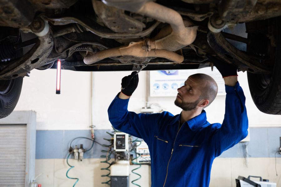 Hombre trabajando en la suspensión de un auto.