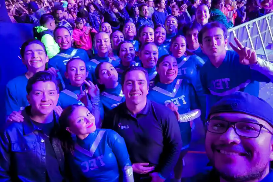 Miembros de la compañía de danza moderna del Tec, campus Hidalgo, junto con profesores y coordinadores, tomándose una foto al cierre del concierto de Belanova, tras su participación en la canción "One, Two, Three, Go!".