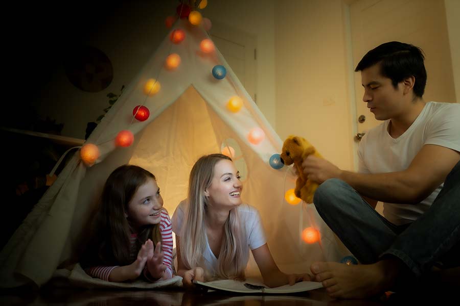 Papá, mamá e hija acampando dentro de la casa