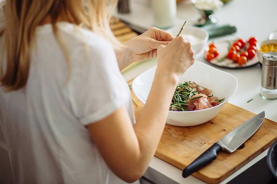 Silueta de una chica cortando verduras en la cocina