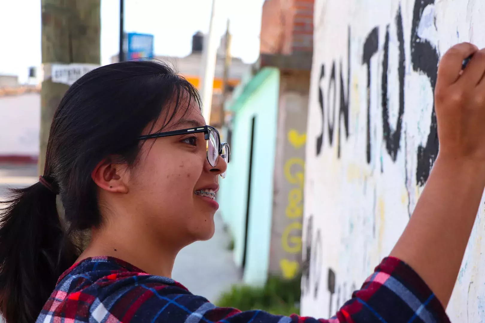 Alumnos y Armando Alanís pintando paredes con frases poéticas